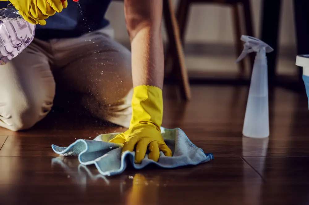 Gloved hands detail-cleaning a hardwood floor